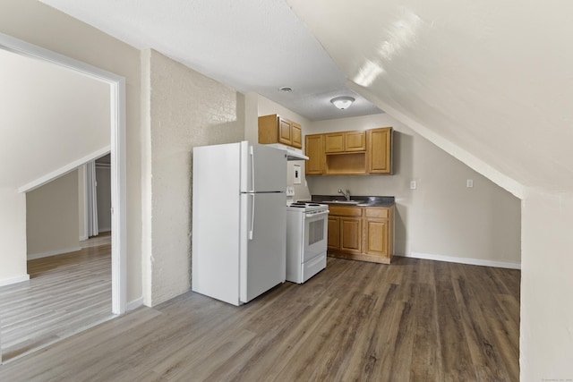 kitchen featuring hardwood / wood-style flooring, white appliances, lofted ceiling, and sink