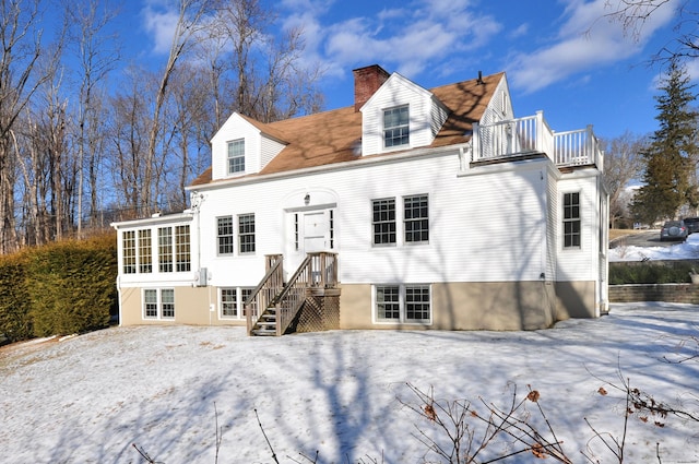 snow covered rear of property with a balcony