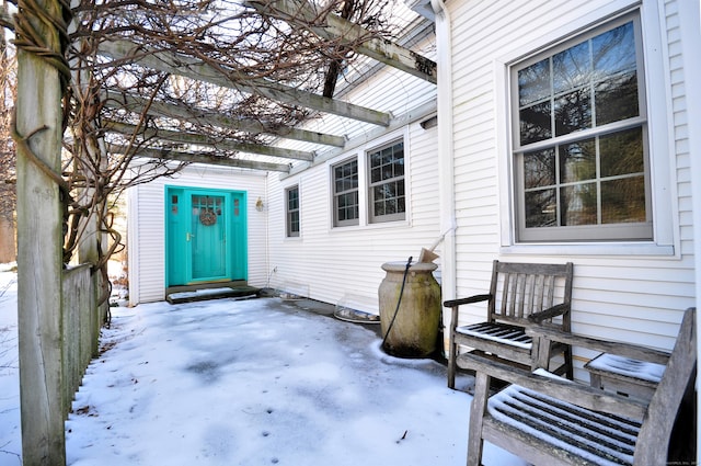 snow covered property entrance featuring a pergola