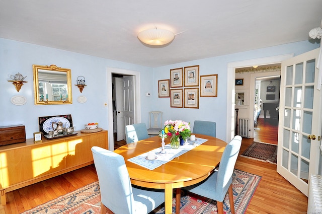 dining room featuring french doors, radiator, and light hardwood / wood-style flooring