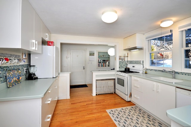 kitchen featuring radiator, sink, white cabinets, light hardwood / wood-style floors, and white appliances