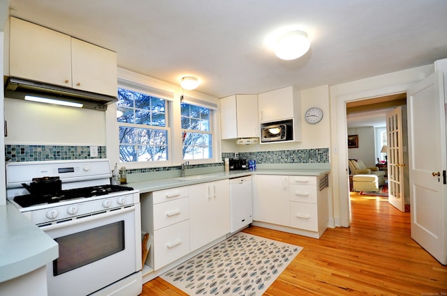 kitchen with tasteful backsplash, white cabinets, exhaust hood, white appliances, and light hardwood / wood-style flooring