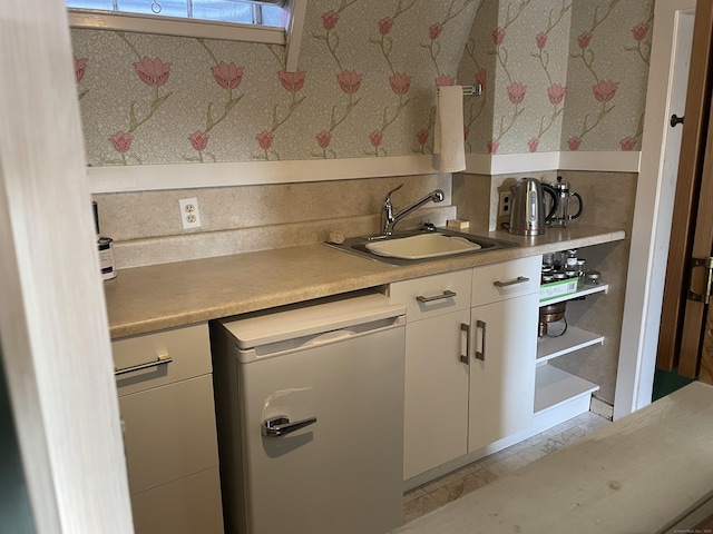 kitchen with dishwashing machine, sink, and white cabinets