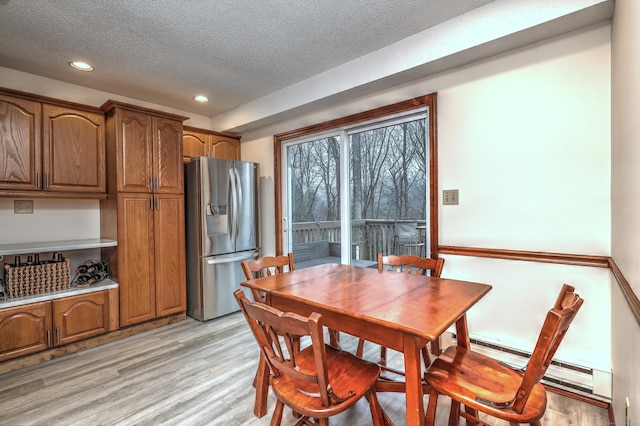 dining area featuring a baseboard heating unit, a textured ceiling, and light hardwood / wood-style flooring