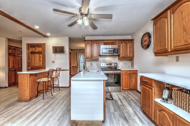 kitchen featuring a breakfast bar, sink, a center island with sink, light hardwood / wood-style flooring, and stainless steel appliances