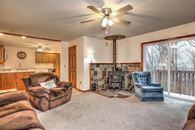 carpeted living room featuring ceiling fan, a textured ceiling, and a wood stove