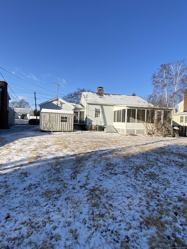 snow covered property featuring central AC and a sunroom