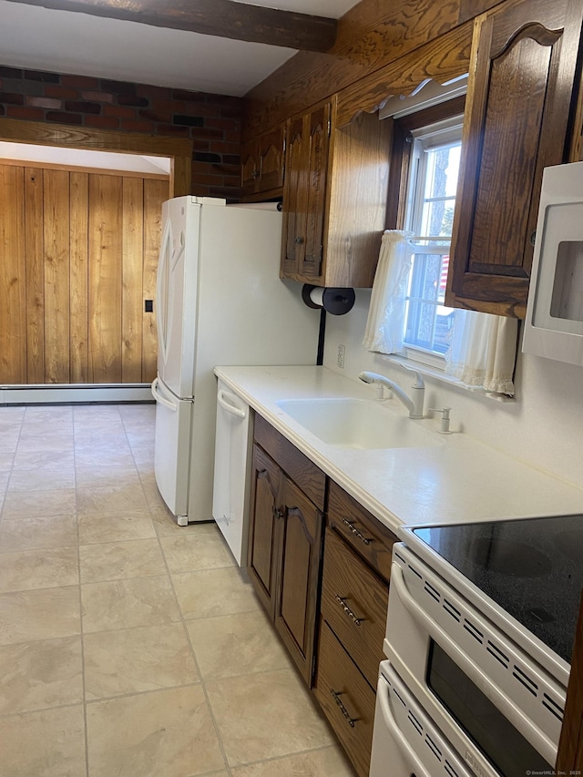 kitchen featuring wooden walls, a baseboard radiator, sink, dark brown cabinetry, and white appliances