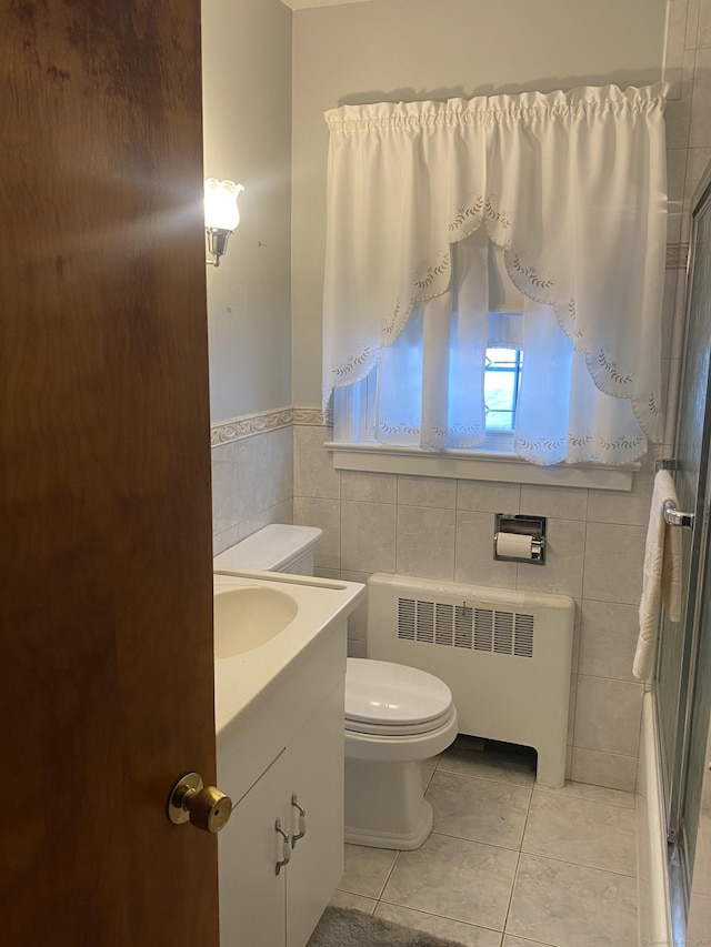 bathroom featuring tile patterned flooring, tile walls, radiator heating unit, vanity, and toilet