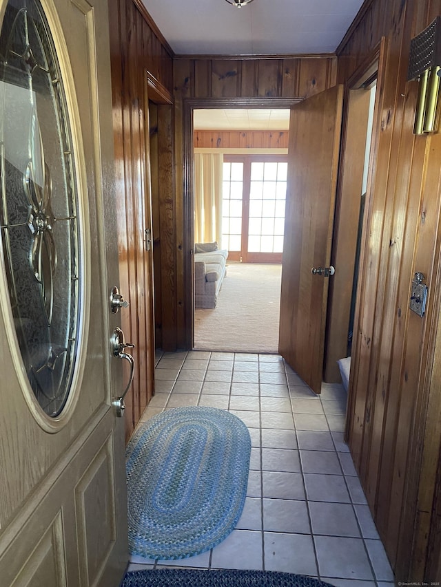 hall with wooden walls and light tile patterned floors