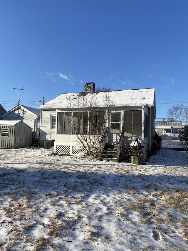 snow covered property with cooling unit and a storage unit