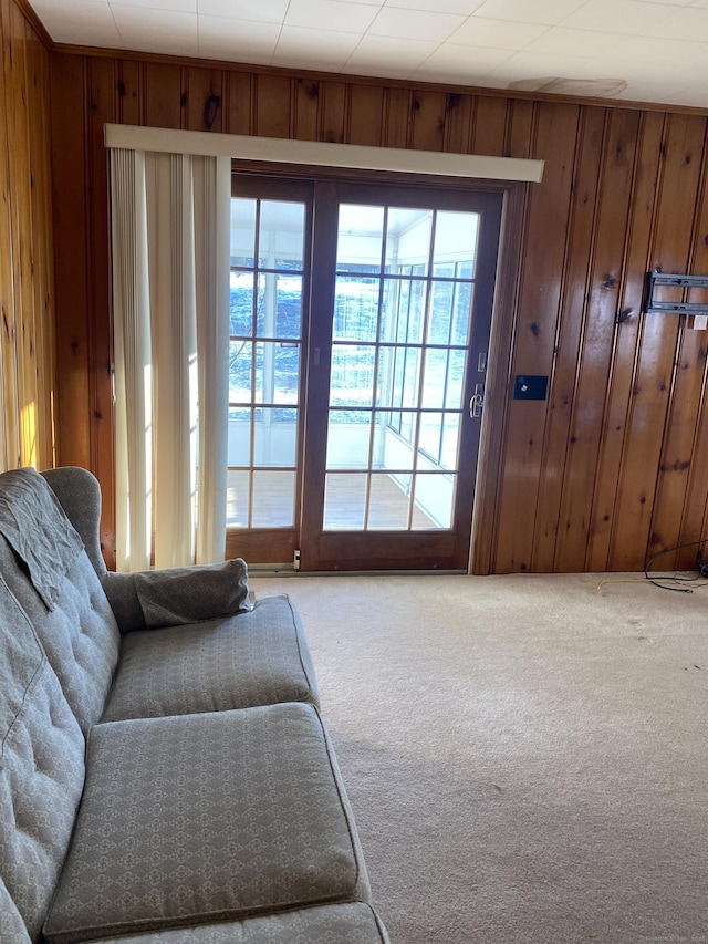 doorway to outside with carpet and wood walls