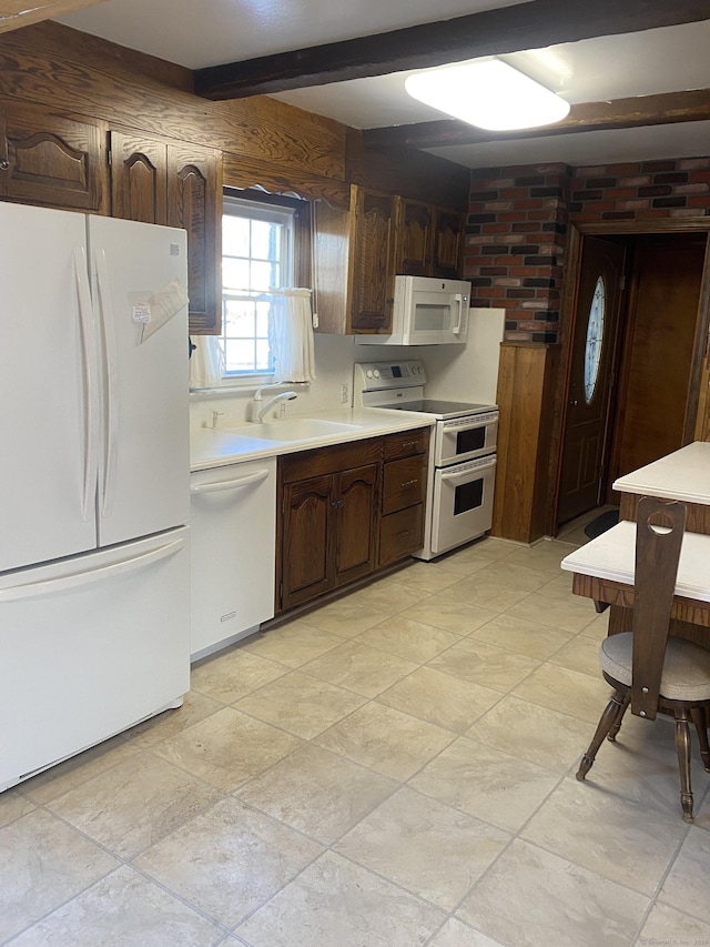 kitchen featuring beam ceiling, dark brown cabinets, sink, and white appliances