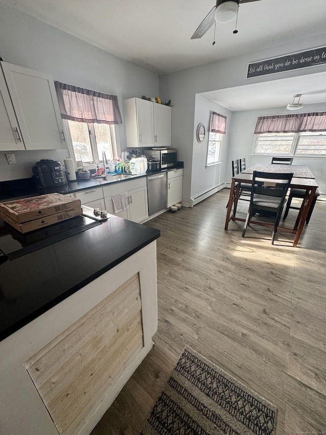 kitchen with sink, white cabinetry, a baseboard radiator, hardwood / wood-style flooring, and stainless steel appliances