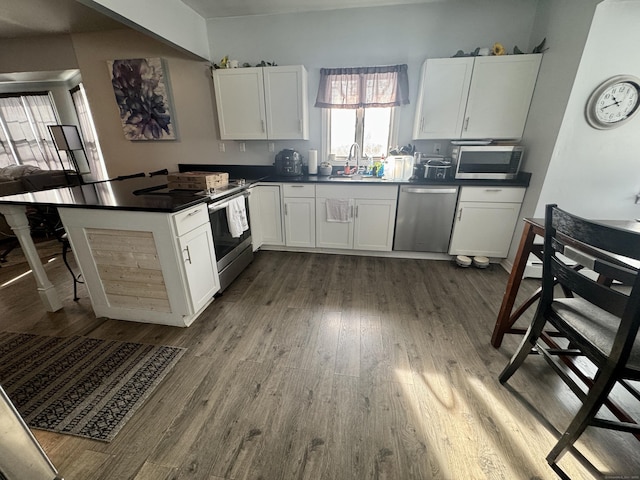 kitchen featuring stainless steel appliances, dark hardwood / wood-style flooring, sink, and white cabinets