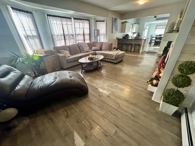 living room with a baseboard heating unit and light wood-type flooring