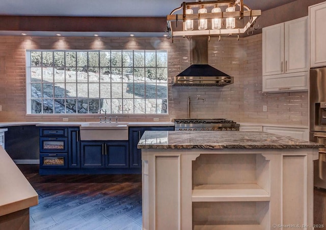 kitchen featuring wall chimney exhaust hood, blue cabinets, white cabinetry, pendant lighting, and light stone countertops