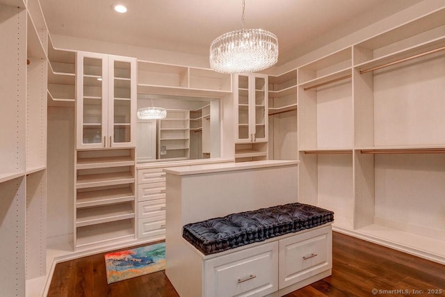 walk in closet with dark hardwood / wood-style floors and an inviting chandelier