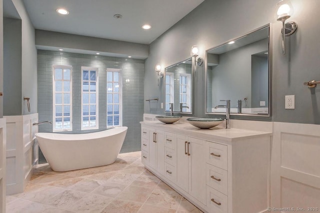 bathroom with vanity, a tub, and tile walls