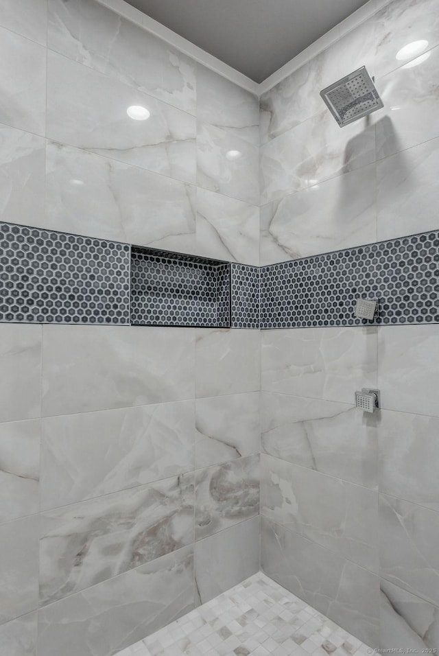 bathroom with a tile shower and ornamental molding