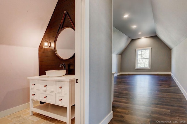 additional living space with vaulted ceiling, wood-type flooring, and sink