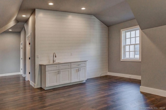 bar with vaulted ceiling, sink, white cabinets, and dark hardwood / wood-style flooring