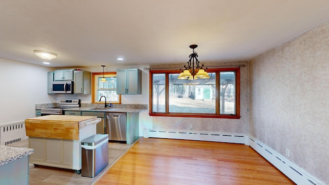 kitchen with stainless steel appliances, decorative light fixtures, sink, and radiator heating unit