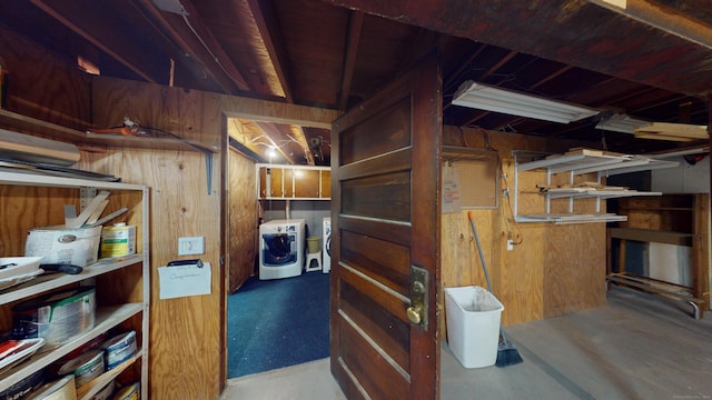 basement featuring wooden walls and washing machine and dryer