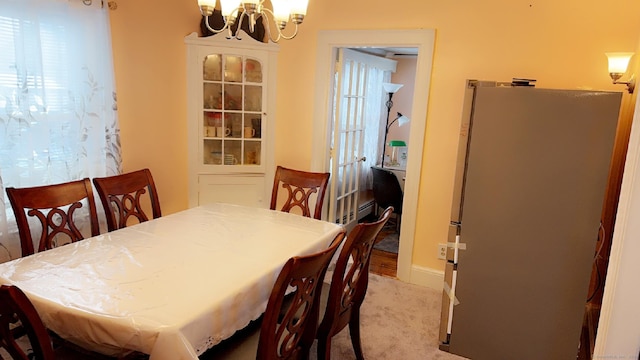 dining area featuring an inviting chandelier, baseboard heating, and carpet floors