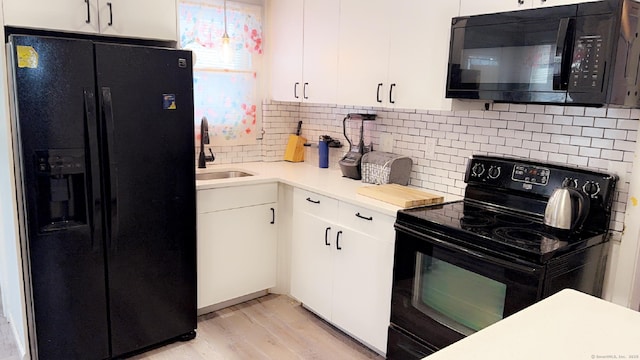 kitchen featuring sink, tasteful backsplash, black appliances, light wood-type flooring, and white cabinets