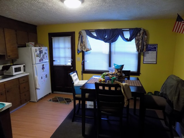 dining room with a textured ceiling and light wood-type flooring