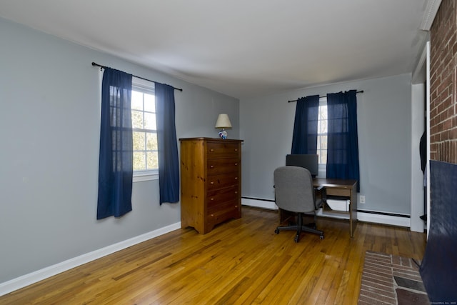 office space with a baseboard heating unit, a wealth of natural light, and hardwood / wood-style floors