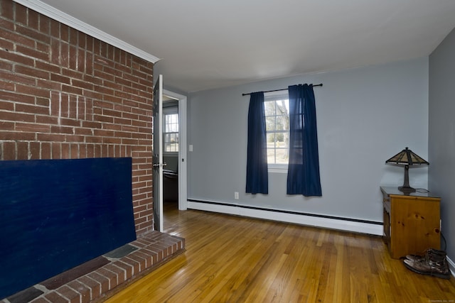 unfurnished living room featuring baseboard heating, a fireplace, and hardwood / wood-style flooring