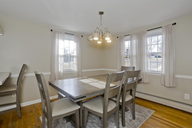 dining area with a baseboard heating unit, hardwood / wood-style floors, and a notable chandelier