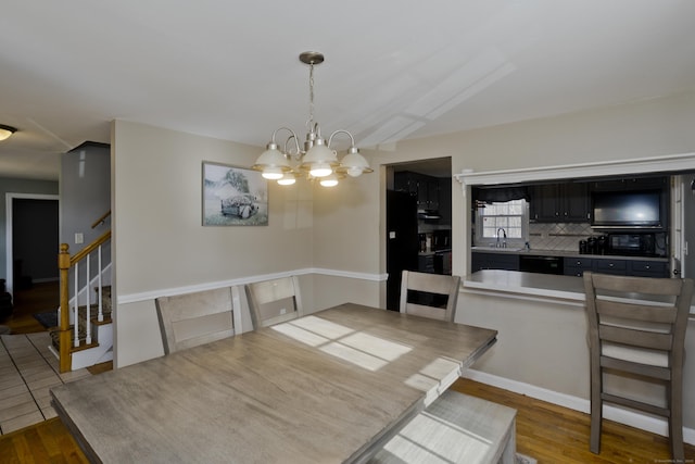 dining room with vaulted ceiling, a chandelier, sink, and hardwood / wood-style floors