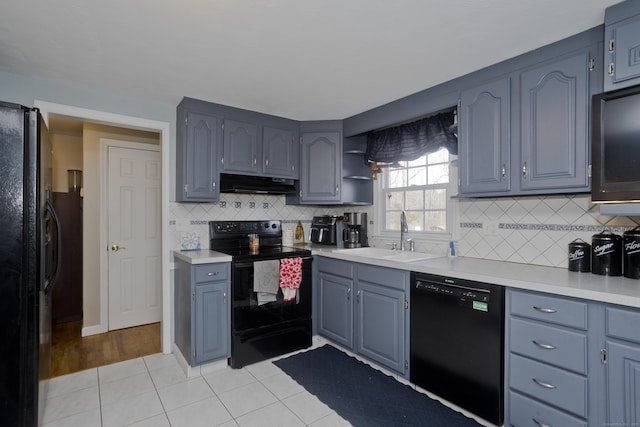 kitchen with backsplash, light tile patterned floors, sink, and black appliances