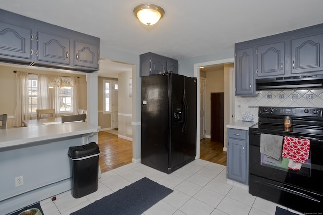 kitchen with tasteful backsplash, gray cabinetry, light tile patterned floors, and black appliances