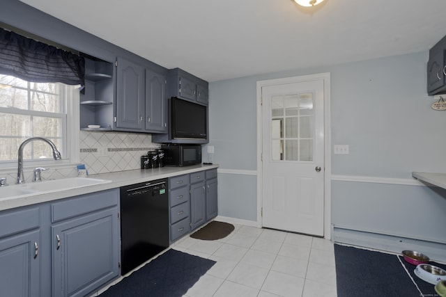 kitchen featuring sink, decorative backsplash, a baseboard heating unit, light tile patterned floors, and black appliances