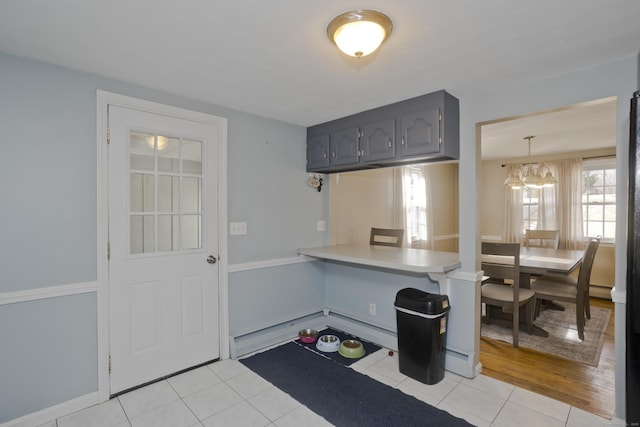 kitchen featuring gray cabinetry, hanging light fixtures, light tile patterned floors, baseboard heating, and kitchen peninsula