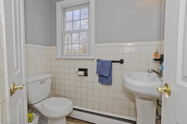 bathroom featuring a baseboard heating unit, tile walls, and toilet