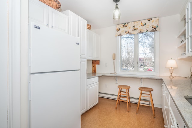 kitchen featuring white cabinetry, light stone counters, decorative light fixtures, baseboard heating, and white fridge