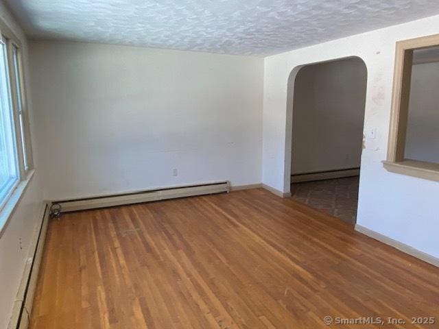 spare room featuring hardwood / wood-style flooring, a baseboard radiator, and a textured ceiling