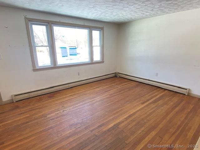 spare room with hardwood / wood-style flooring, a baseboard heating unit, and a textured ceiling