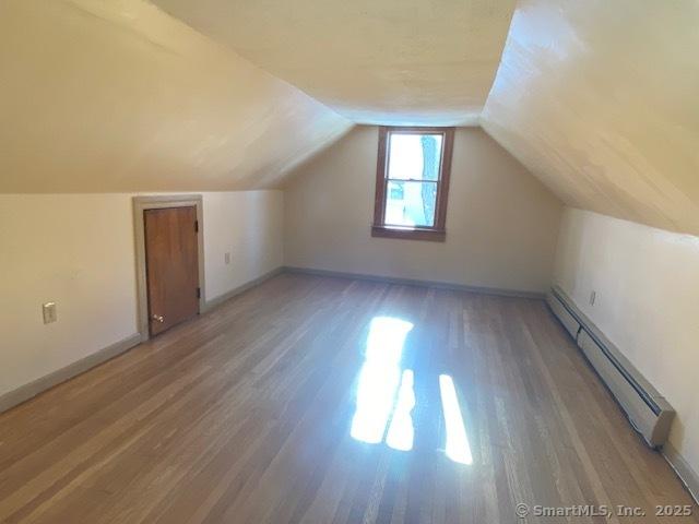 additional living space featuring lofted ceiling, a baseboard radiator, and wood-type flooring