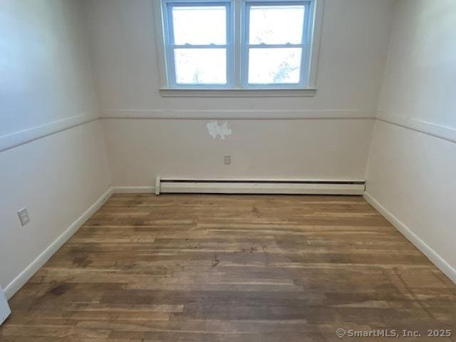 spare room featuring wood-type flooring and baseboard heating