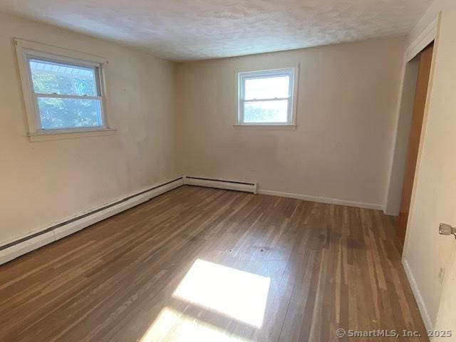 spare room featuring hardwood / wood-style floors, a textured ceiling, and a baseboard heating unit