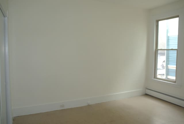 unfurnished room with baseboards, a baseboard heating unit, and a wealth of natural light