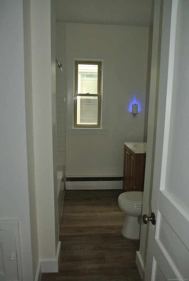 full bath featuring a baseboard radiator, toilet, vanity, wood finished floors, and baseboards