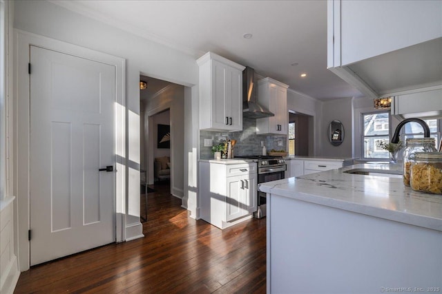 kitchen featuring stainless steel range with gas cooktop, sink, white cabinets, backsplash, and wall chimney exhaust hood