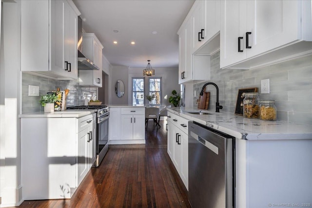 kitchen with sink, appliances with stainless steel finishes, dark hardwood / wood-style floors, kitchen peninsula, and white cabinets